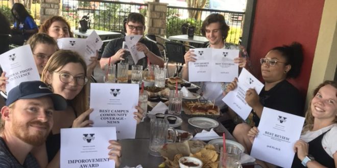 The Spectator staff holds printed copies of their awards